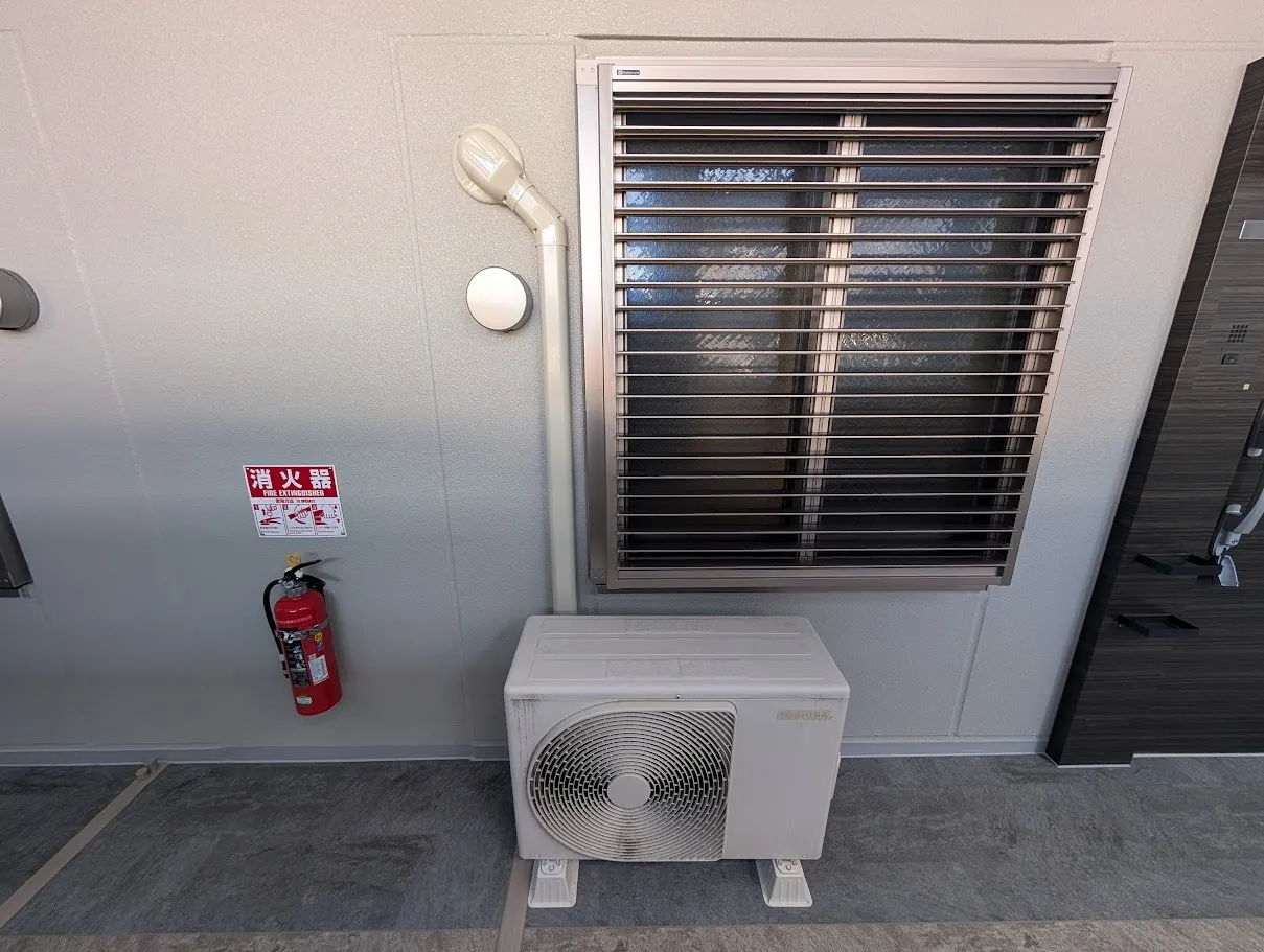 御新築マンション：玄関横の室外機です、通路に面していますので屋外化粧カバーで綺麗に仕上げました